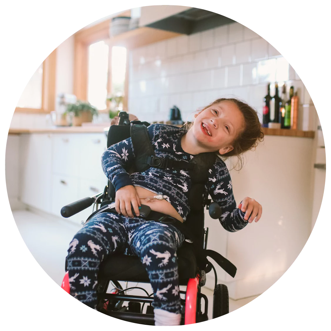 A young girl with a physical disability is sitting in her specialised wheelchair indoors