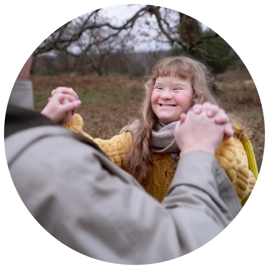 A young woman with down syndrome is smiling while having fun at the park with her care giver